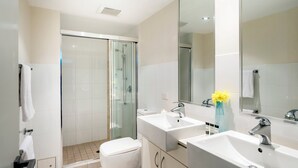 A modern bathroom with a glass-enclosed shower, two sinks, and a large mirror.