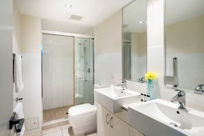 A modern bathroom with a glass-enclosed shower, two sinks, and a large mirror.