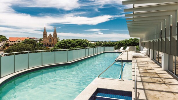 A swimming pool with a view of a church and a modern building.