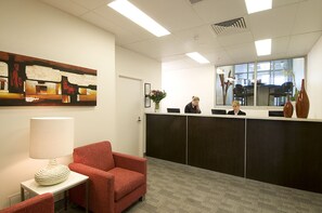 A reception area with a desk, chairs, a painting, and a window with a view.