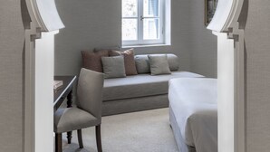 A bedroom with a built-in desk, a bed, and a window with blinds.