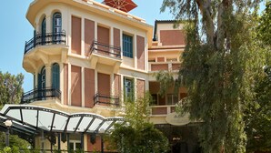 A multi-story building with balconies, a distinctive red roof, and a sign indicating it is a hotel.
