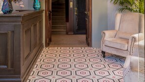 A grand entrance with a chandelier, a staircase, and a patterned floor.
