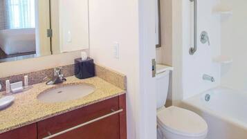 A bathroom with a sink, mirror, toilet, and shower.