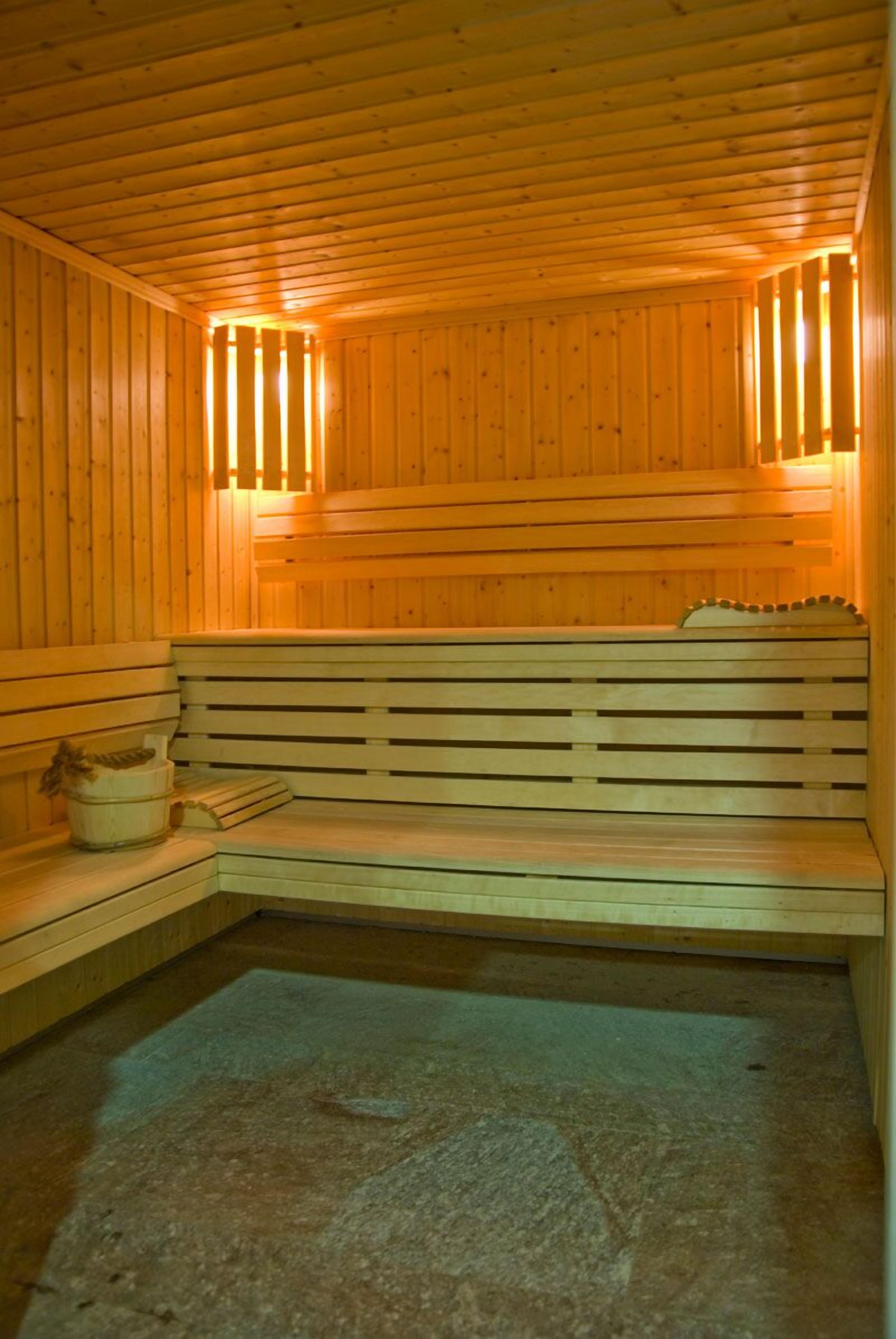 A wooden sauna with benches and a stone floor.