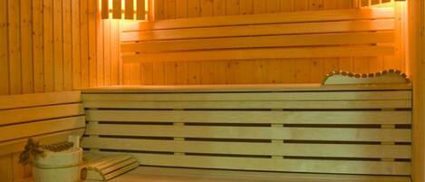 A wooden sauna with benches and a stone floor.