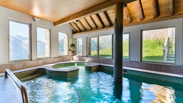 Zona de spa con jacuzzi, ventanas amplias y vistas a las montañas.