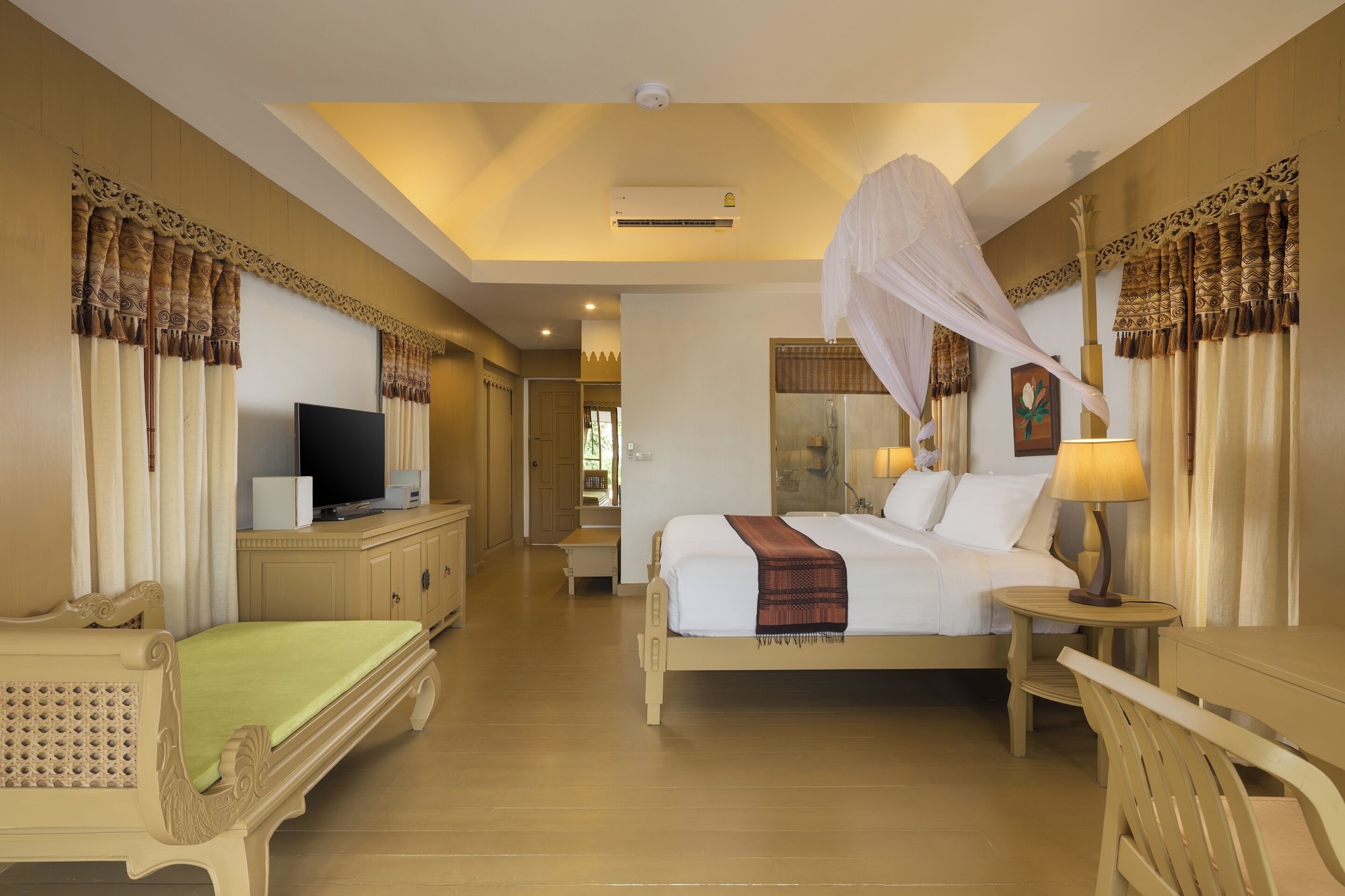 A hotel room with a bed, bedside table, lamp, TV, and wardrobe.