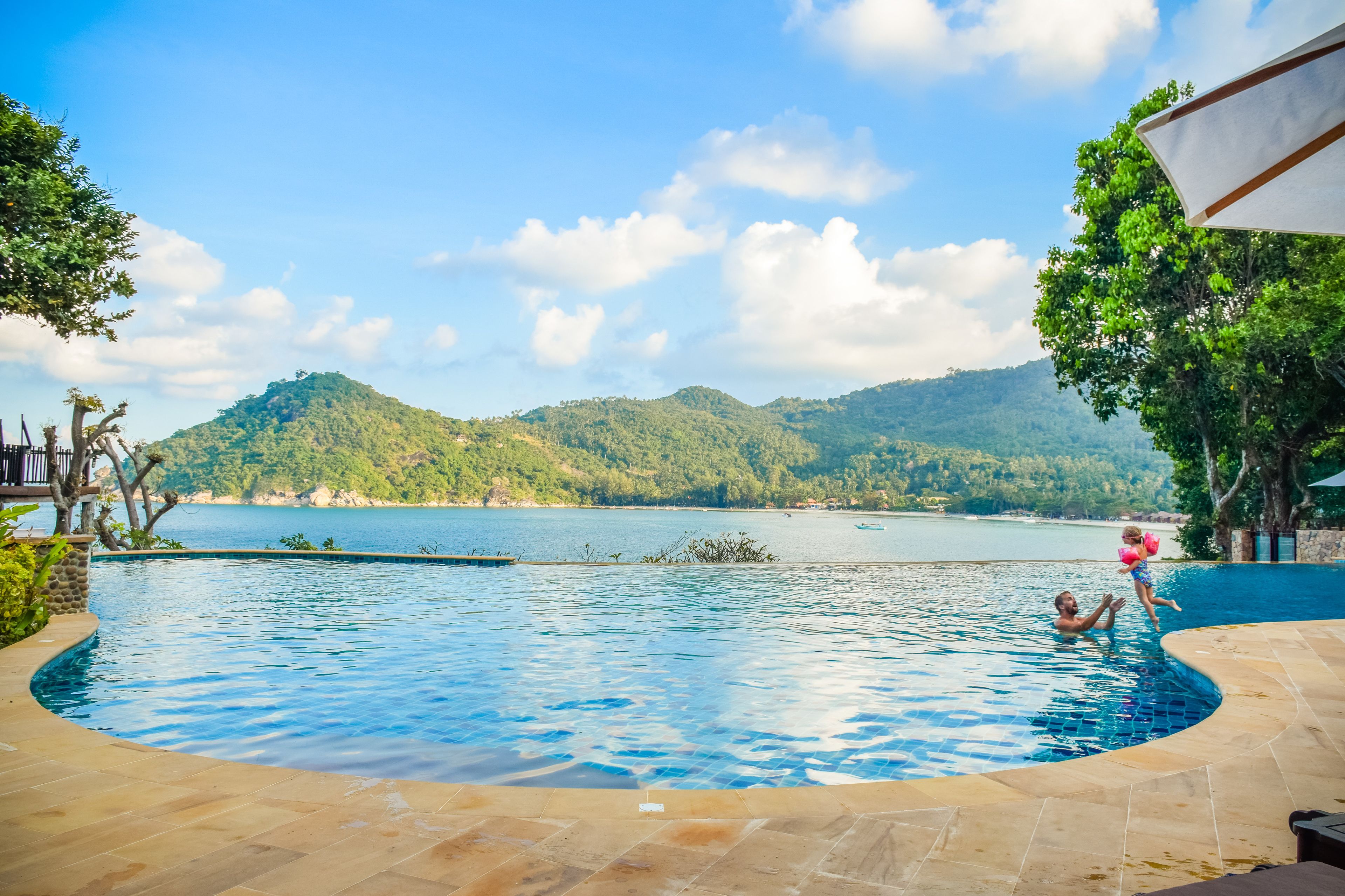 A swimming pool with a view of a lake and mountains.