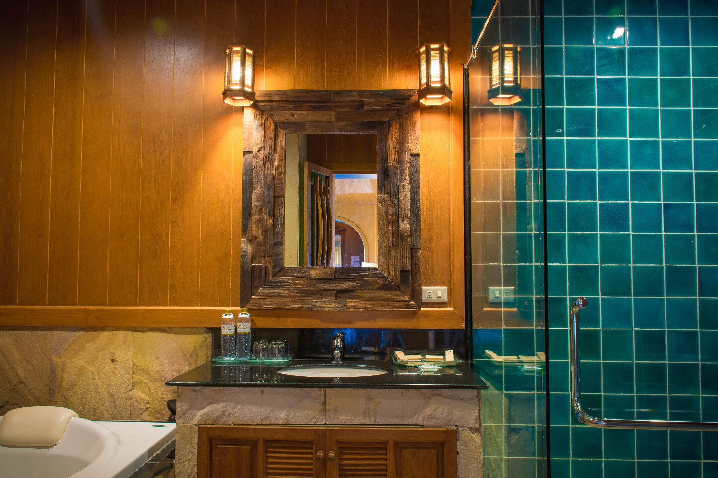 Un baño con tocador de madera, lavamanos y cabina de ducha con mampara de vidrio.