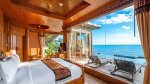 Un dormitorio amplio con una cama grande, un balcón con piscina y vista al océano.