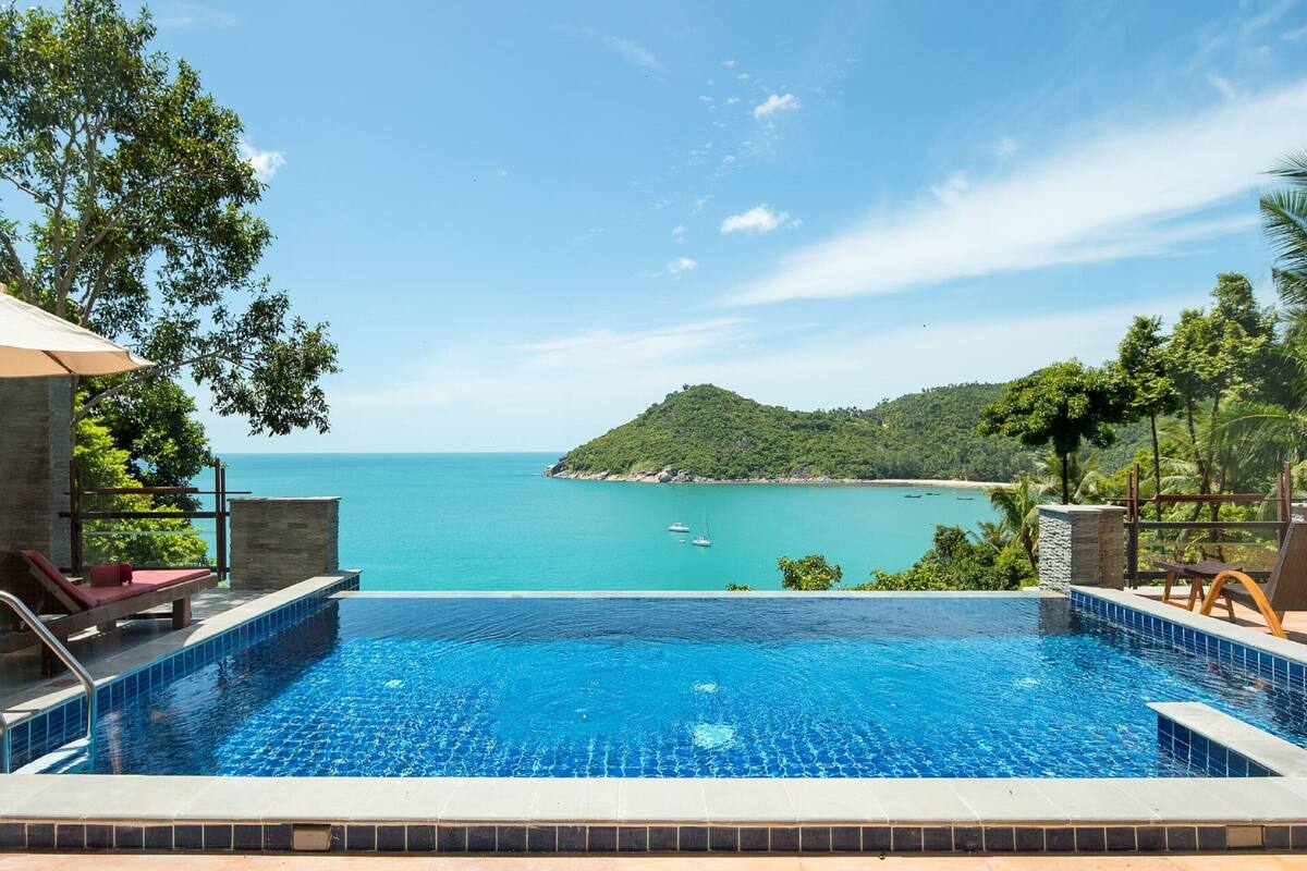 A swimming pool with a view of the sea and a small island.
