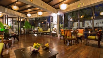 A spacious indoor area with wooden flooring, multiple seating arrangements, and large windows allowing natural light.