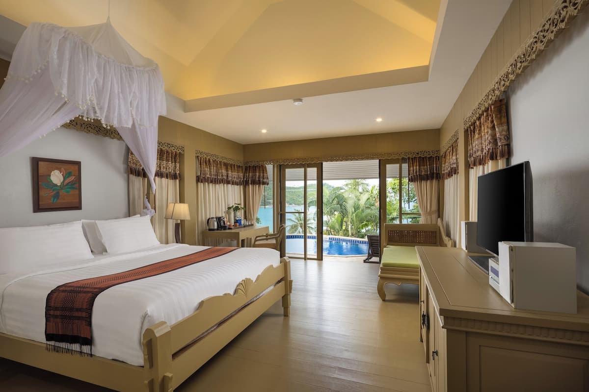 A hotel room with a bed, a TV, a desk, and a view of the outdoors.