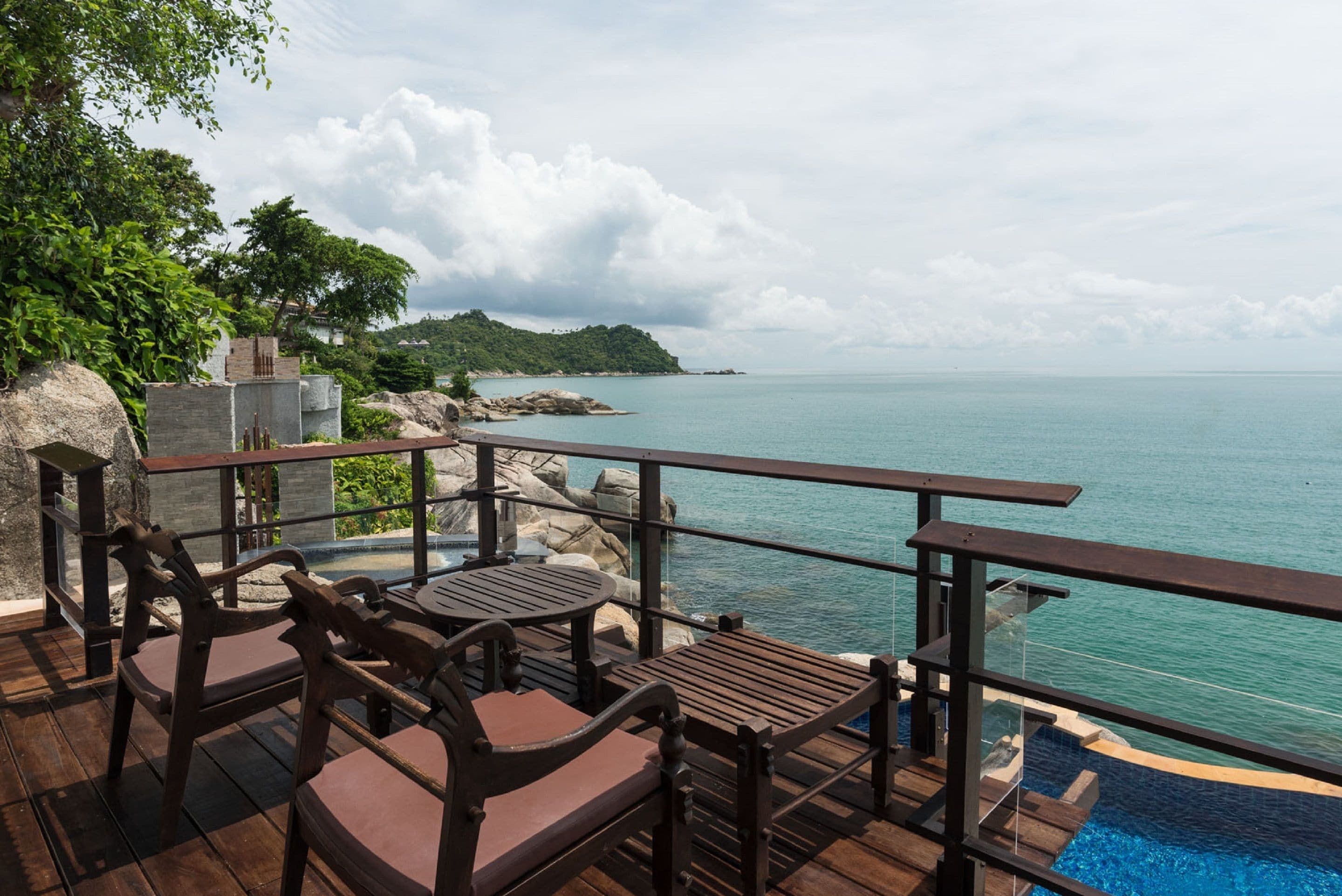 A wooden deck with outdoor furniture overlooking a calm sea and a distant island.