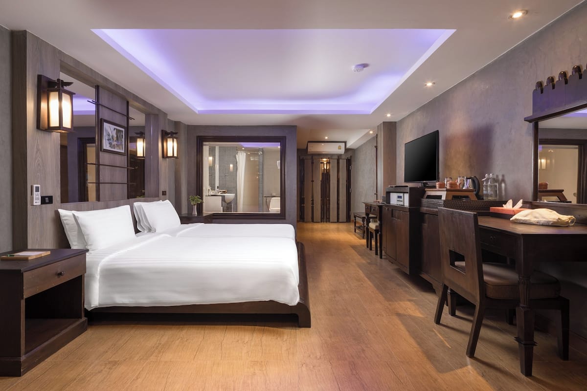 A modern hotel room with a large bed, a desk, and a television.