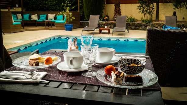 A dining table with a pool view, outdoor seating, and a dessert setup. - Hostellerie La Bergerie du Cap (Agde)