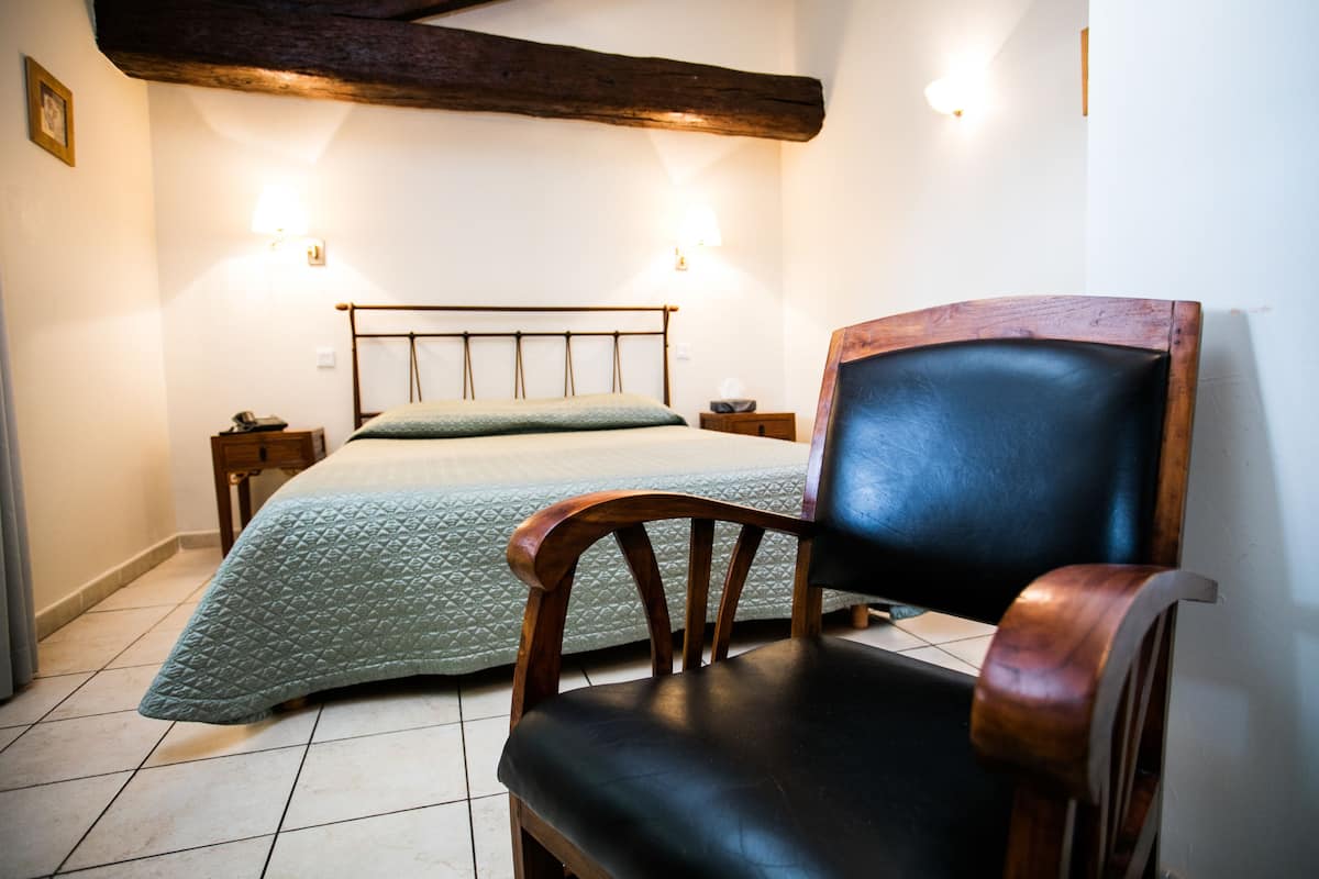 Ein Schlafzimmer mit einem Bett, einem Holzstuhl und zwei Nachttischen.