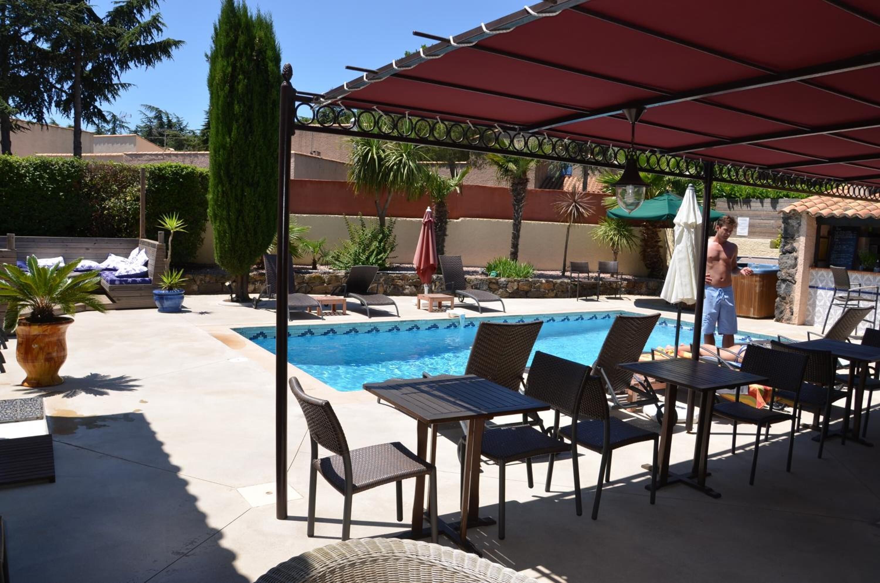 A poolside area with lounge chairs, a table, and a covered seating area.