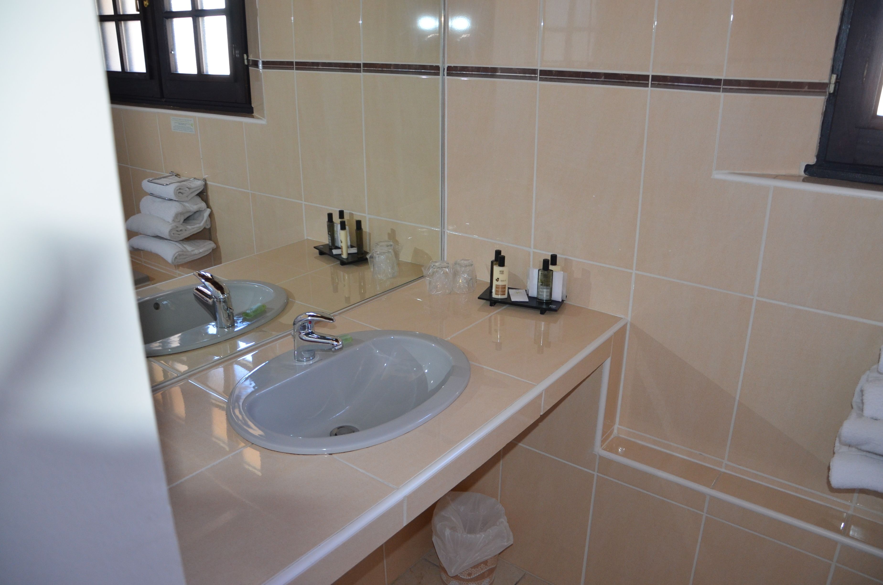 Un baño con lavamanos, espejo y toallero.