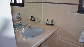 Un baño con lavamanos, espejo y toallero.