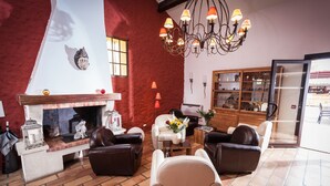 A living room with a fireplace, leather sofas, a coffee table, and a chandelier. - Hostellerie La Bergerie du Cap (Agde)