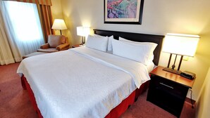 A hotel room with a large bed, two bedside lamps, a chair, a nightstand, and a painting on the wall. - Holiday Inn Reynosa Zona Dorada by IHG (Reynosa)