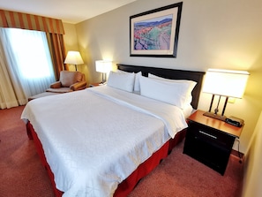 A hotel room with a large bed, two bedside lamps, a chair, a nightstand, and a painting on the wall. - Holiday Inn Reynosa Zona Dorada by IHG (Reynosa)