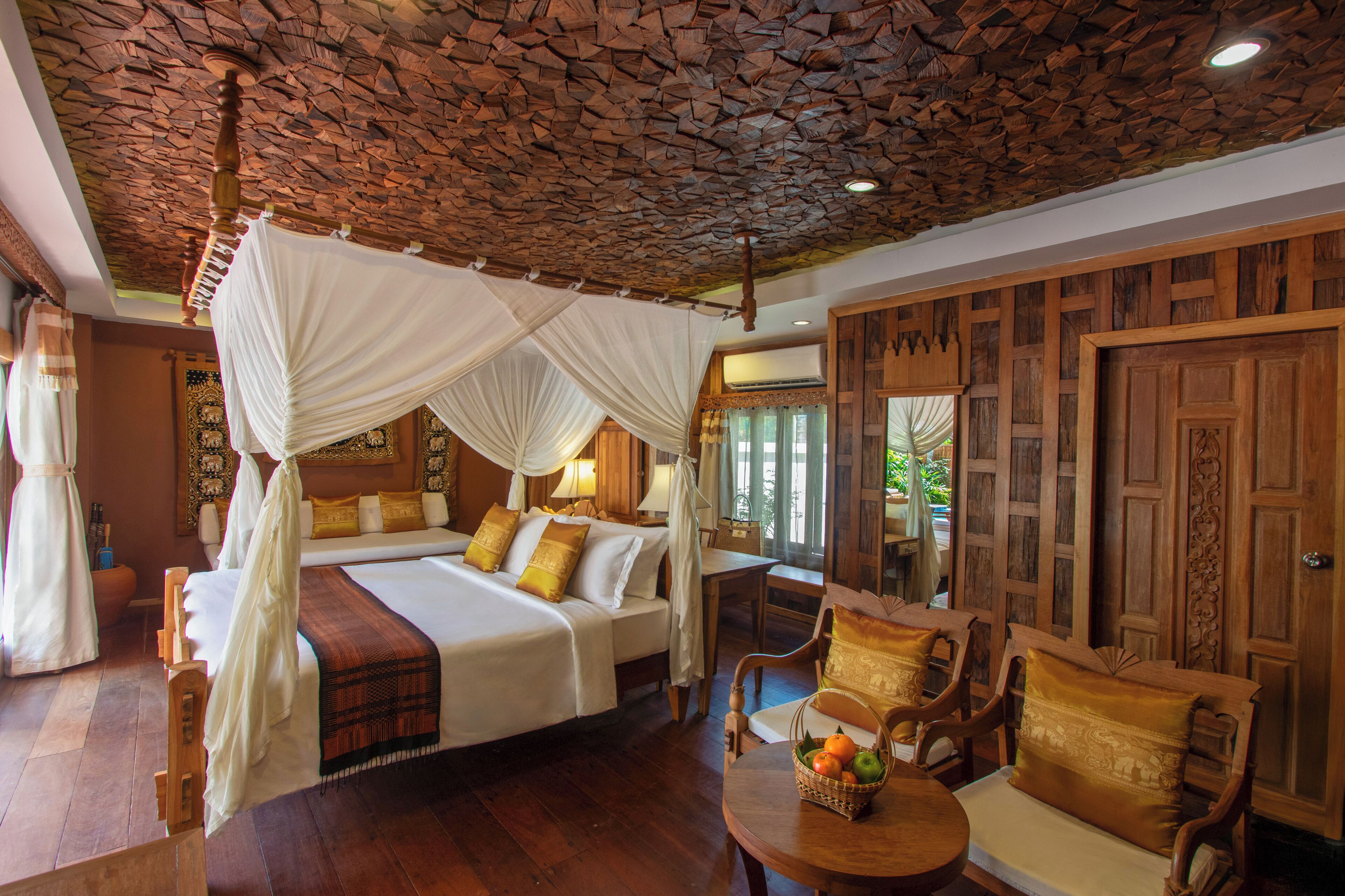 Una habitación con cama con dosel, muebles de madera y techo de piedra.