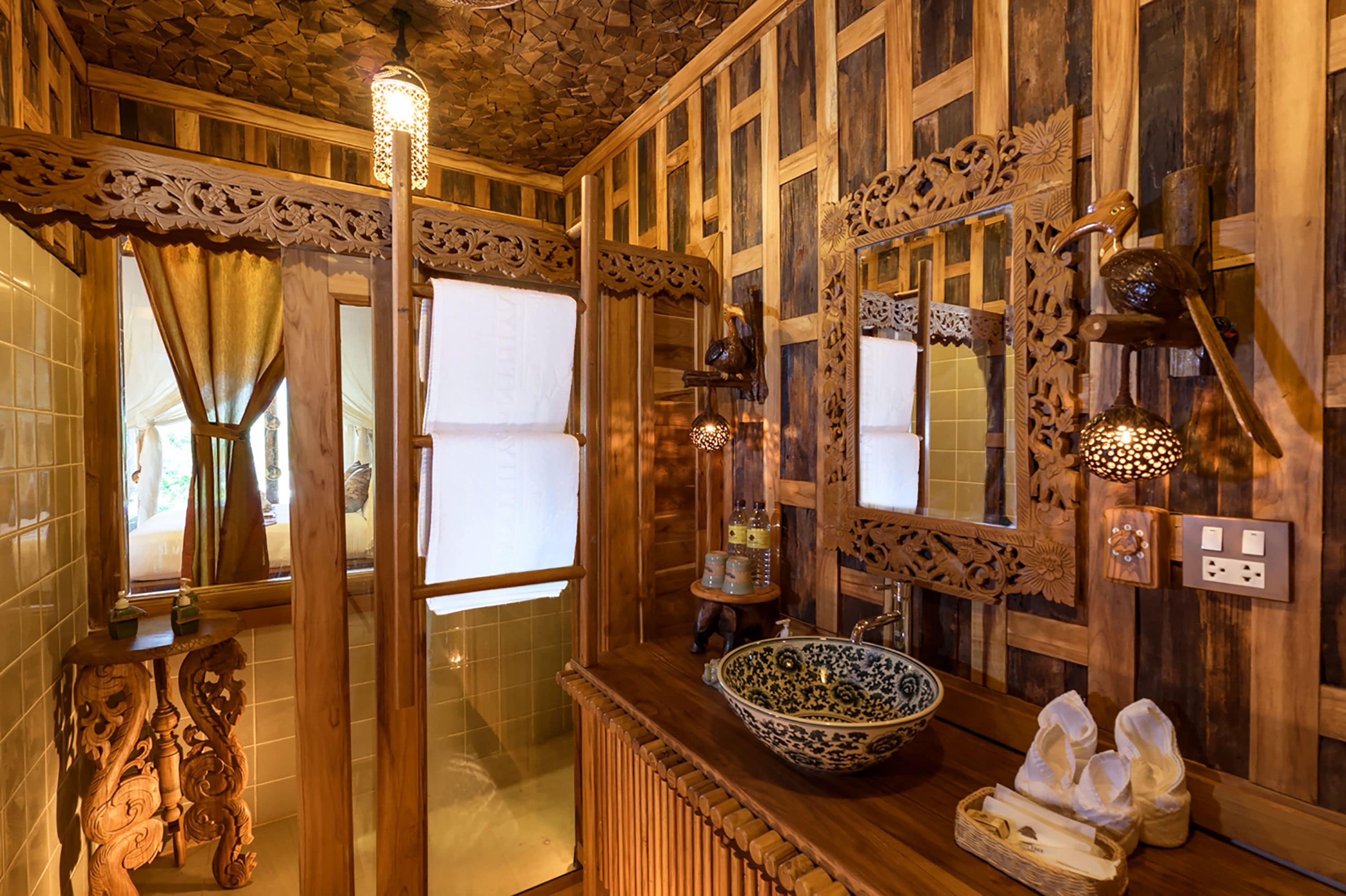Ein Badezimmer aus Holz mit einem großen Spiegel, einem Waschbecken und einer dekorativen Leuchte.