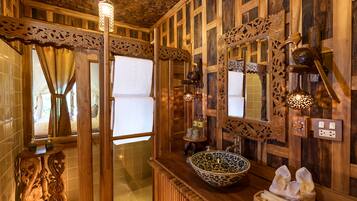 Ein Badezimmer aus Holz mit einem großen Spiegel, einem Waschbecken und einer dekorativen Leuchte.