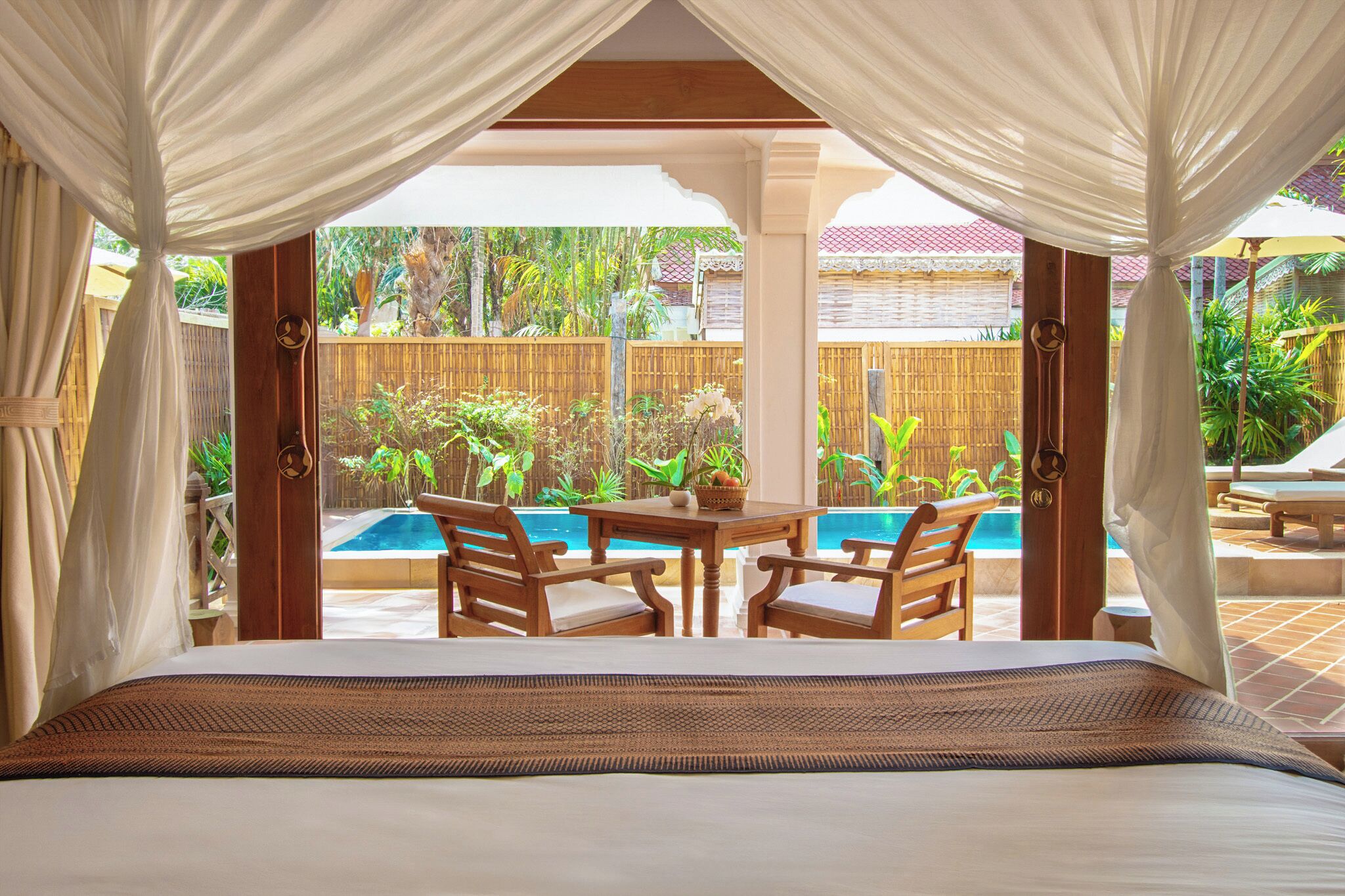 A bedroom with a view of a pool and outdoor seating.