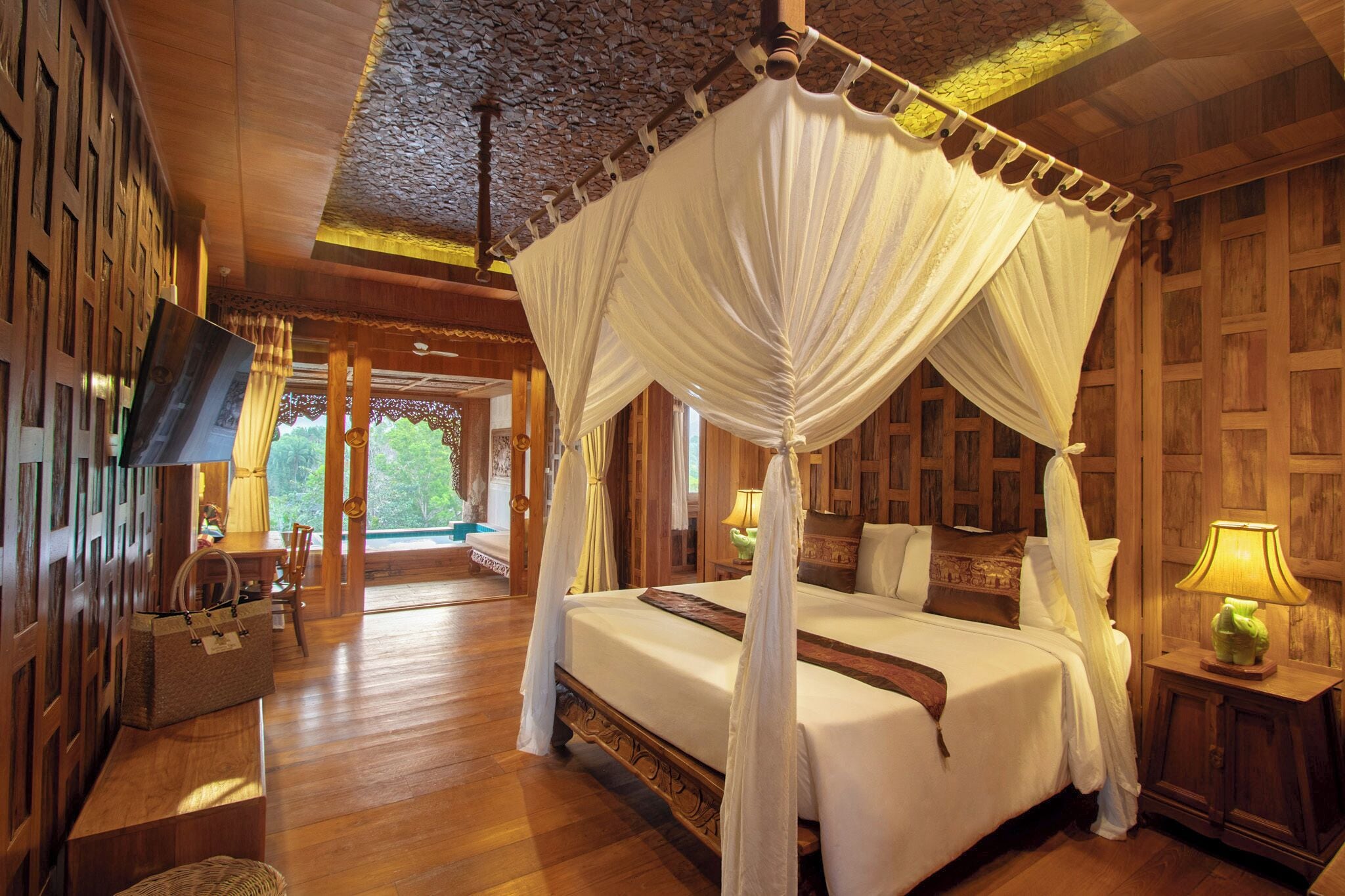 A four-poster canopy bed with a wooden headboard, a wooden floor, and a stone ceiling.