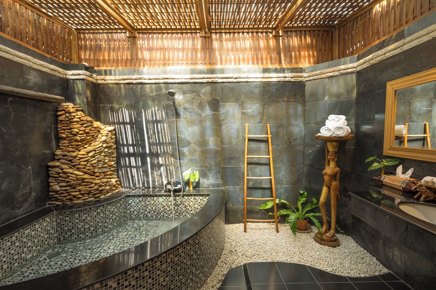 A bathroom with a stone wall, a wooden ladder, a sink, and a mirror.