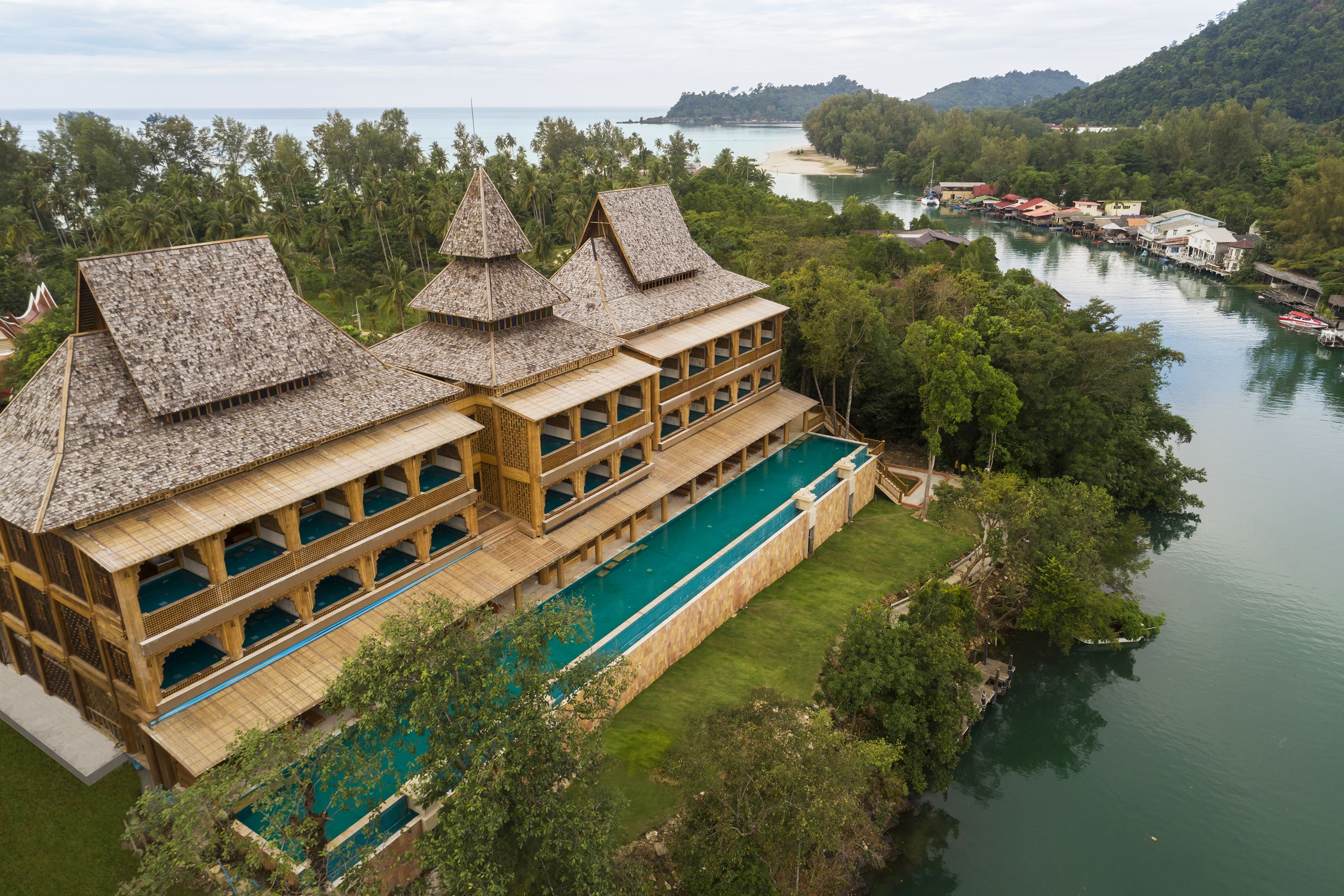 Un resort con varias construcciones, una piscina larga y vista al río.
