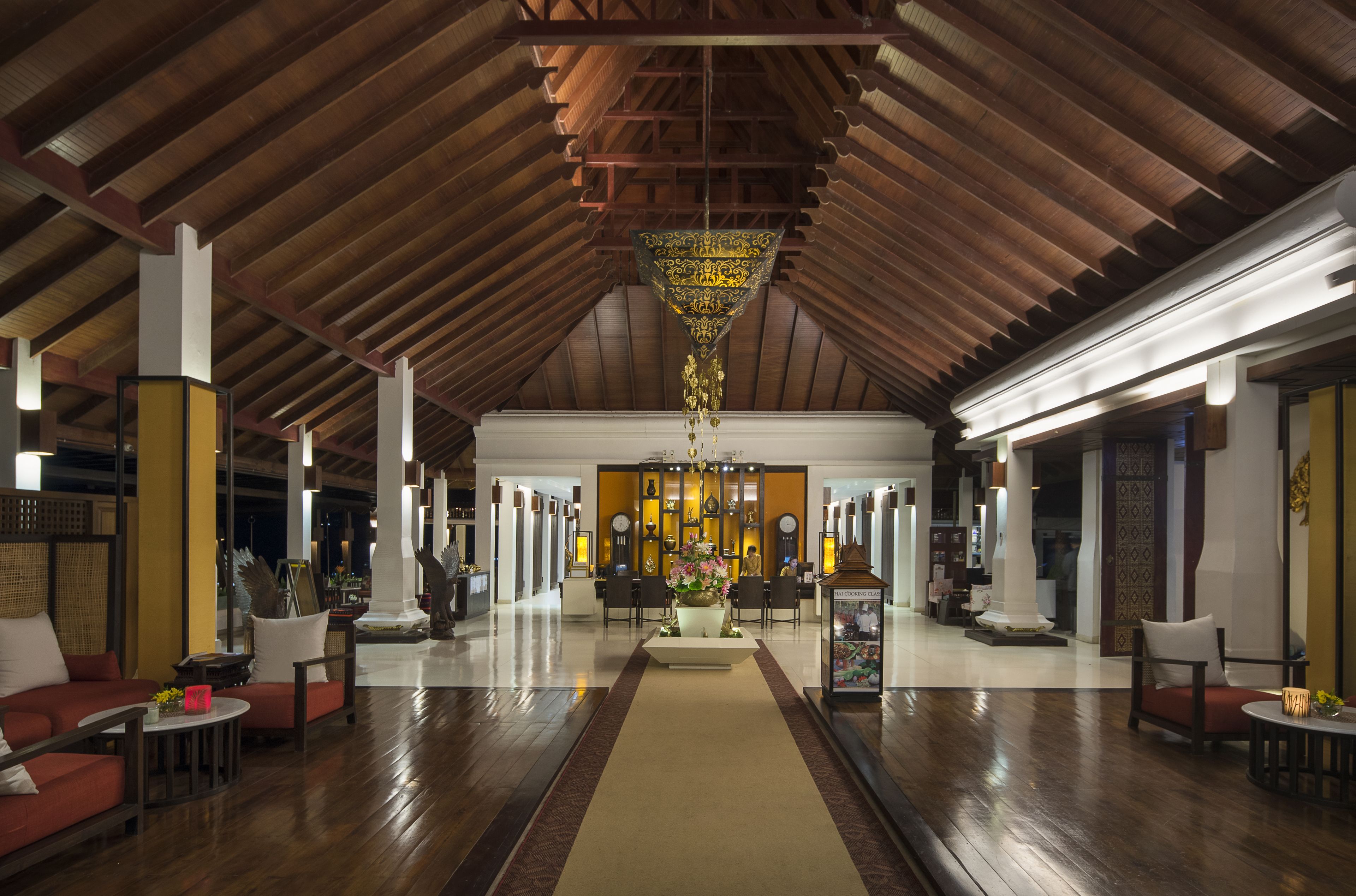 A spacious lobby with a high wooden ceiling, a central chandelier, and a variety of seating arrangements.