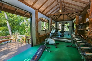 A gym with exercise equipment, a bench, and a view of the outdoors.