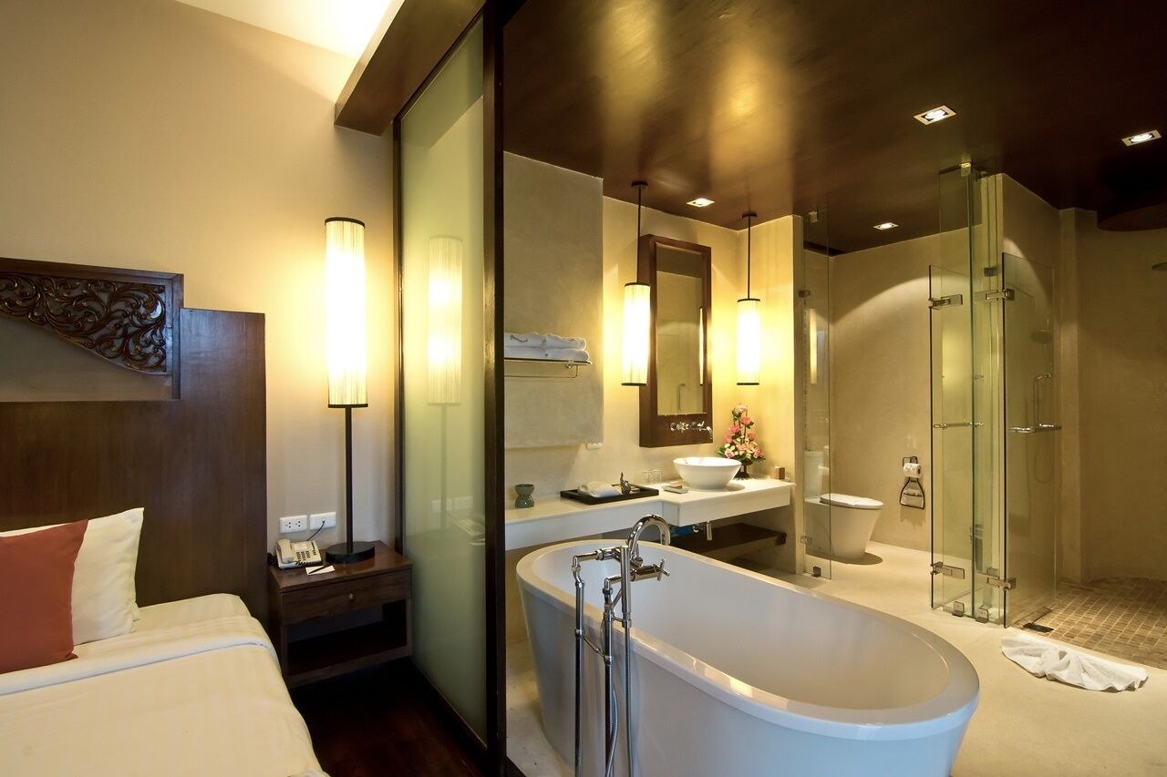 Een moderne badkamer met een ruime badkuip, een douche met glazen wand en een apart toilet.