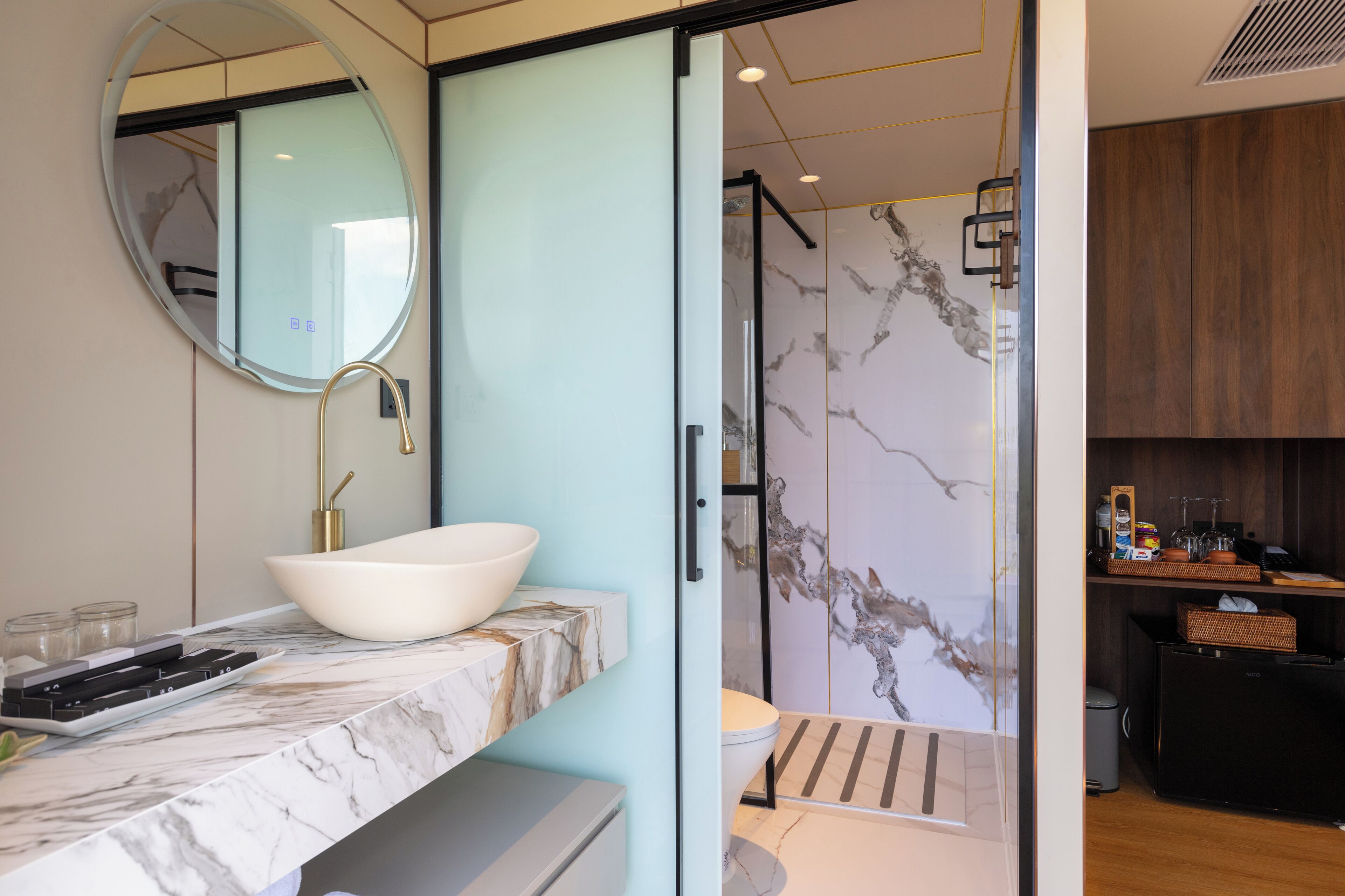 A modern bathroom with a white sink, marble countertop, and a large mirror.