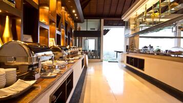 A buffet setup with multiple serving stations, a polished marble countertop, and a view of the outdoors through a large window.