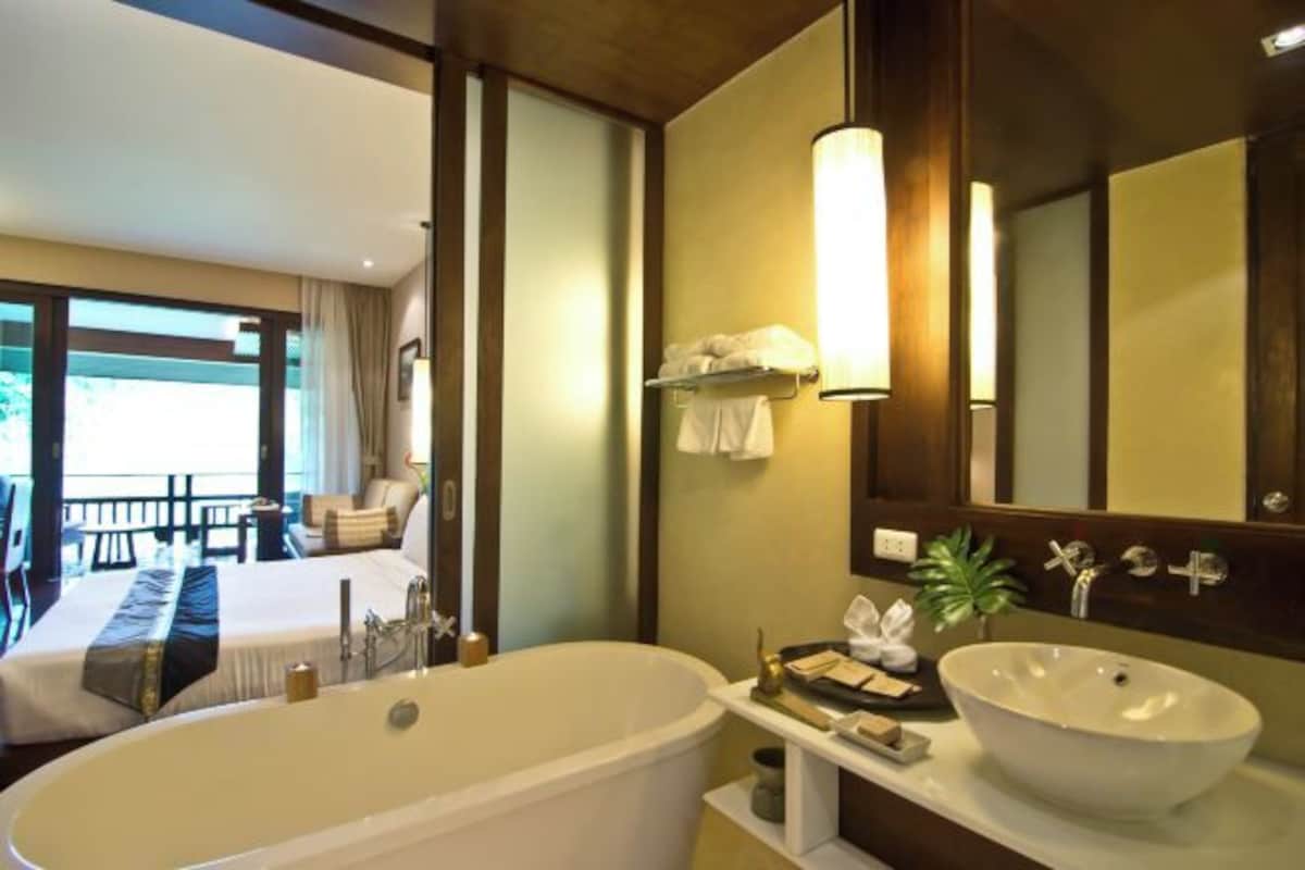 A modern bathroom with a freestanding bathtub, a large mirror, and a vanity with a bowl sink.