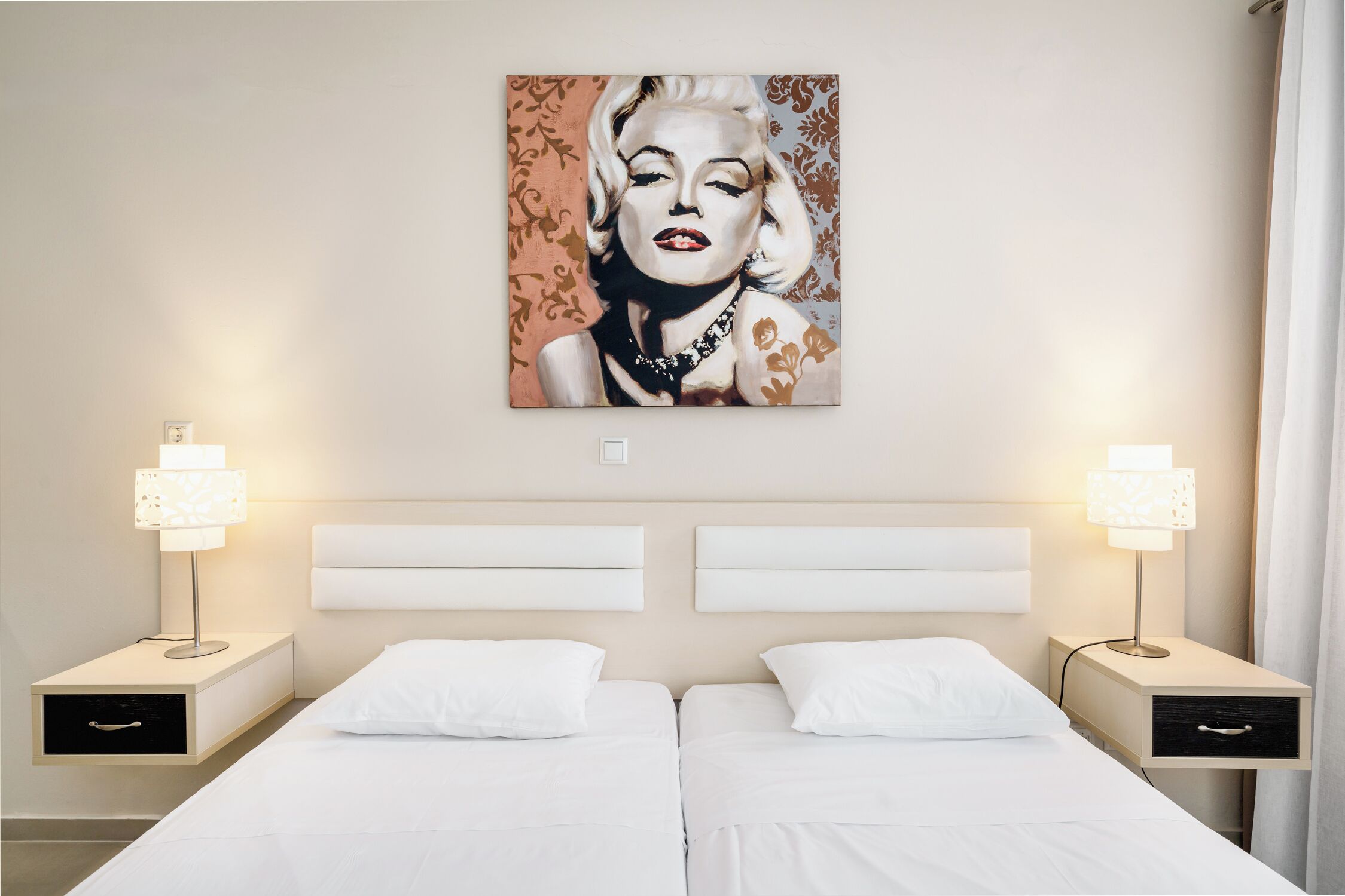 A hotel room with two beds, white bedding, a large portrait on the wall, and bedside lamps.