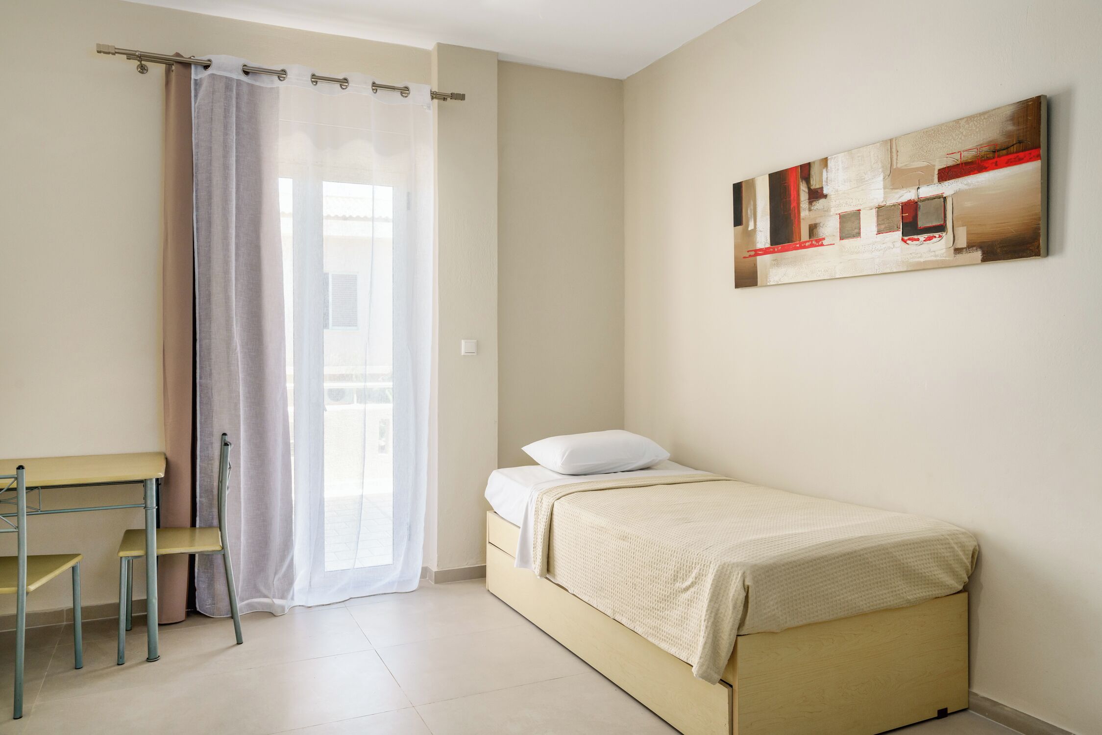 A bedroom with a bed, a desk, and a chair.