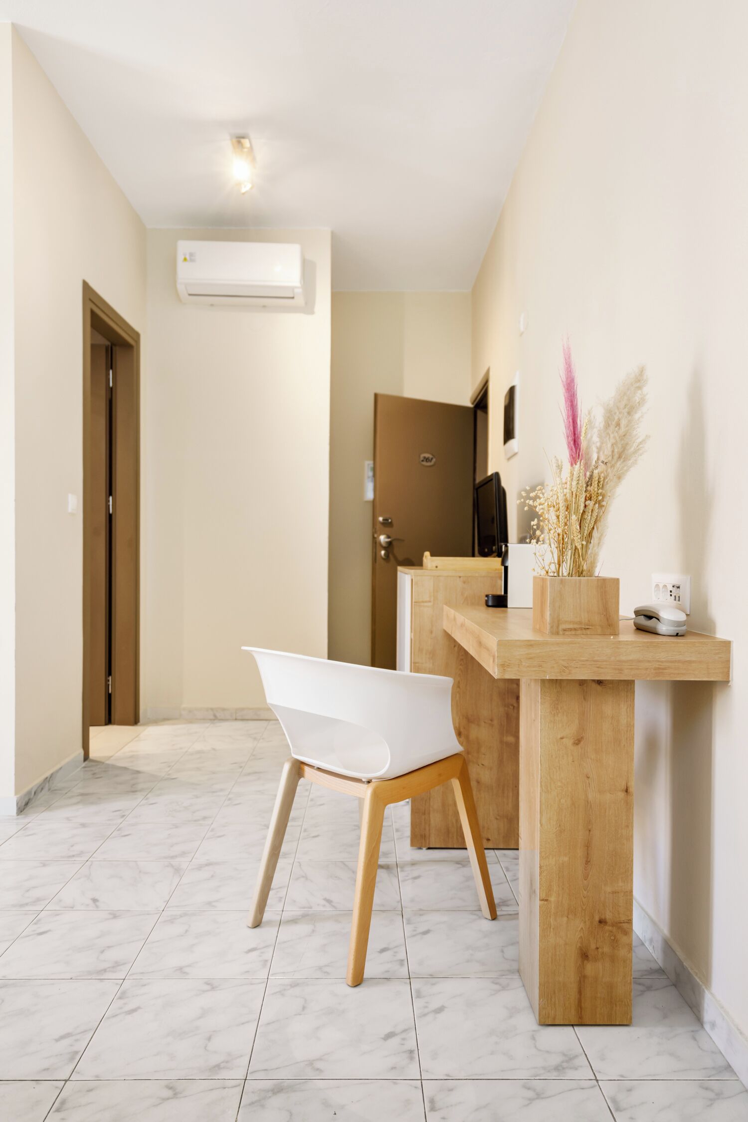 A modern bathroom with a white bathtub, wooden vanity, and a vase with dried flowers.