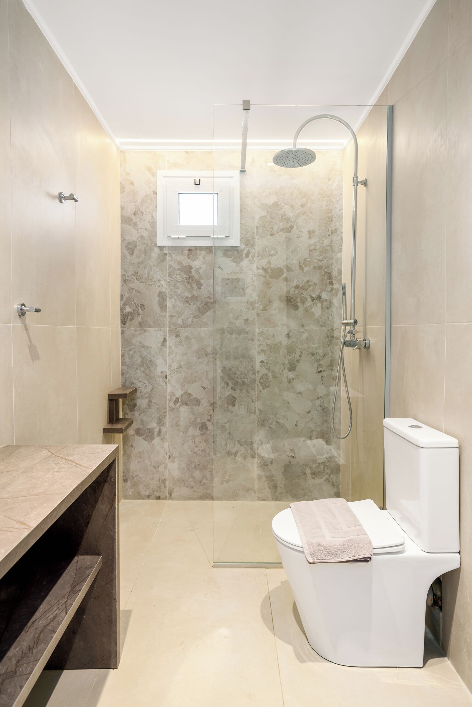 Ein modernes Badezimmer mit einer Duschkabine, einer Toilette und einem Waschtisch mit Marmorplatte.