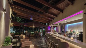 A bar area with wooden beams, bar stools, and a counter with bottles. - Axos Hotel (Rethymno)