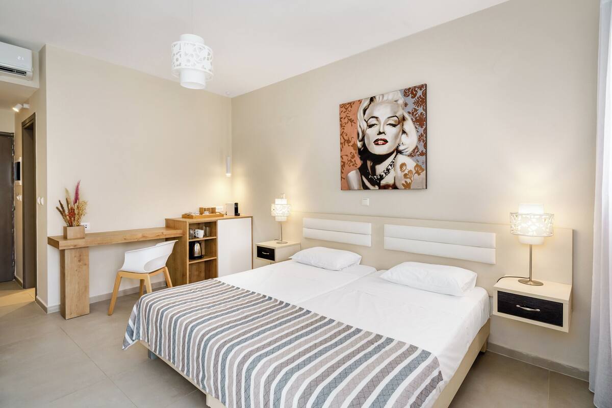 Ein modernes Hotelzimmer mit einem großen Bett, einem Schreibtisch, einem Sessel und einem Wandbild.