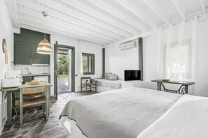 Ein Schlafzimmer mit einem Bett, einem Fernseher, einem Schreibtisch mit Stuhl und einem Fenster.