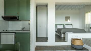 A room with a bed, a small kitchenette, and a bathroom.