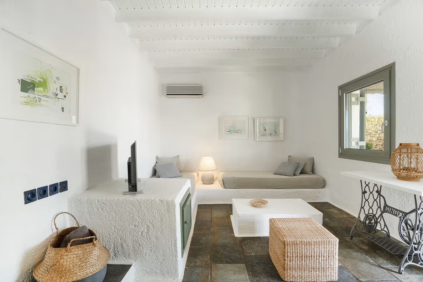 A cozy living room with a sofa, a TV, a lamp, and a wicker basket.